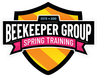 A shield-shaped logo with orange and yellow stripes. Text reads Beekeeper Group in bold white letters and Spring Training 2026 in pink on a banner. ESTD 2010 appears at the top in blue, highlighting baseball lessons for the season.
